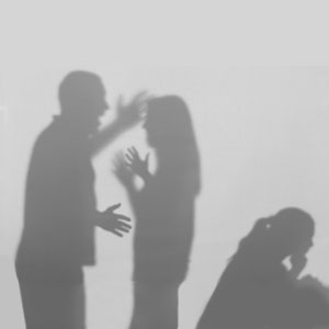 A man and woman stand facing each other, their shadows cast on the ground. The image relates to 'Dealing With Domestic Violence Charges. - The Law Office Of Michael D. Barber